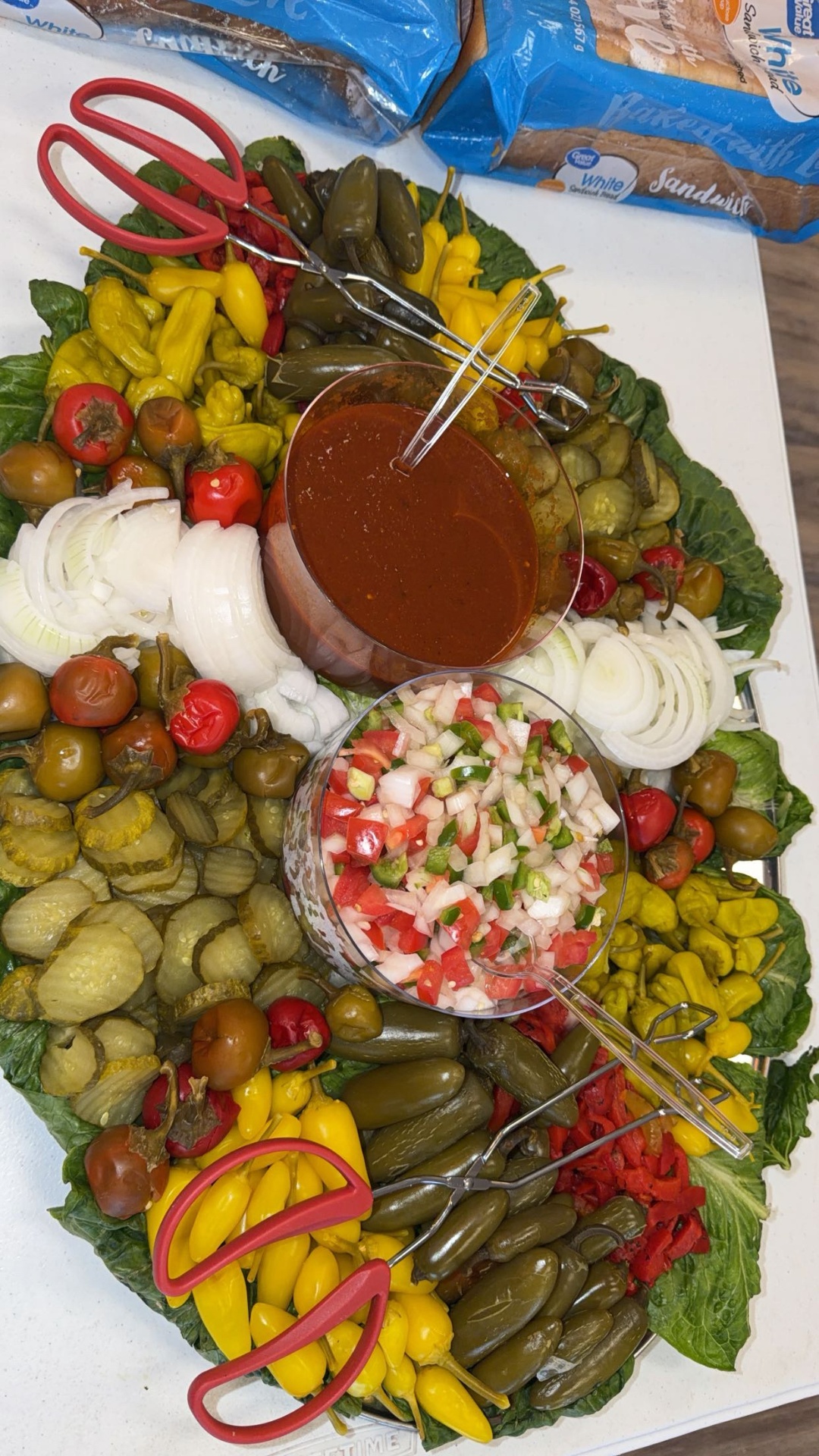 Large lettuce-lined catering tray of pickles, peppers and house BBQ sauce
